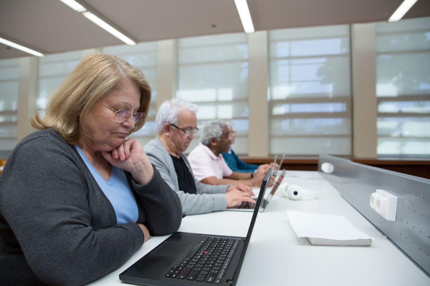 Diverse group of older adults focused on laptops in a technology class